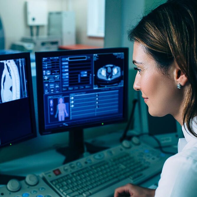Doctor looking at medical charts on her computer monitors.