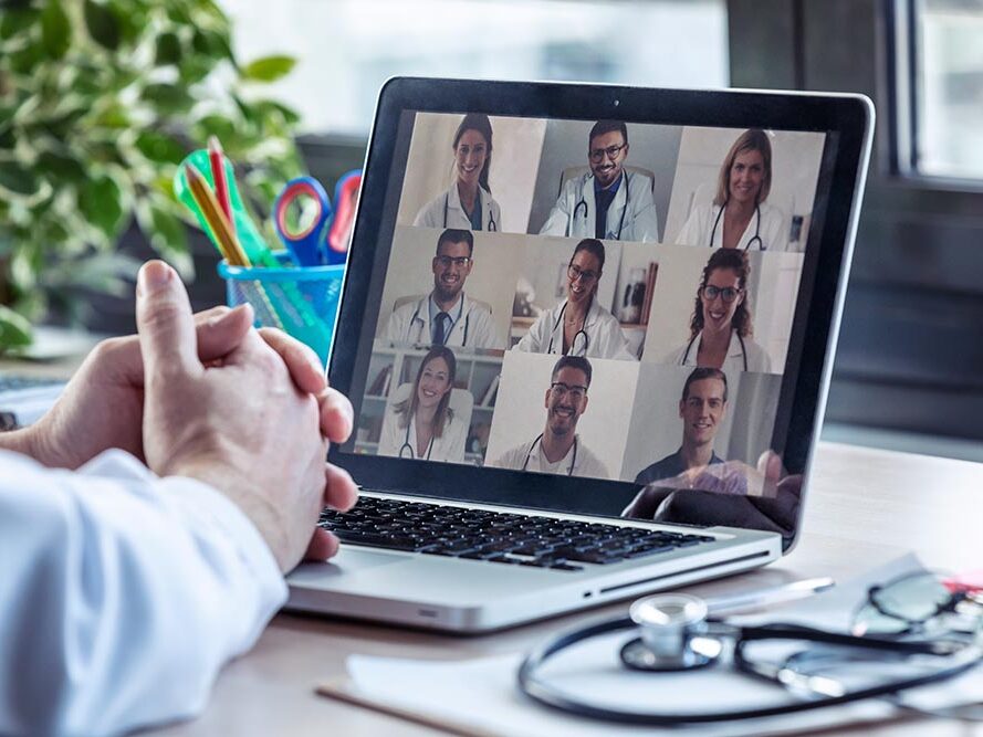 Doctor having video conference on laptop with his colleagues at home.